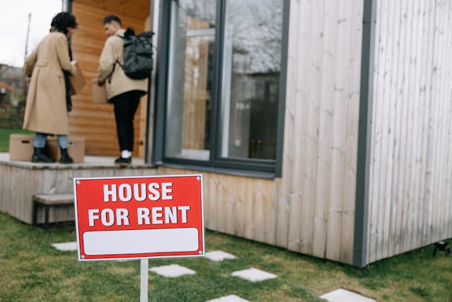 house-for-rent-sign-with-people-moving-in-to-house
